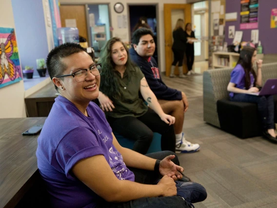 Members of LGBTQ sitting in common area smiling for a photo