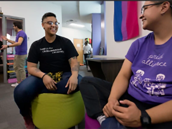 Two members of LGBTQ smiling and talking in common area