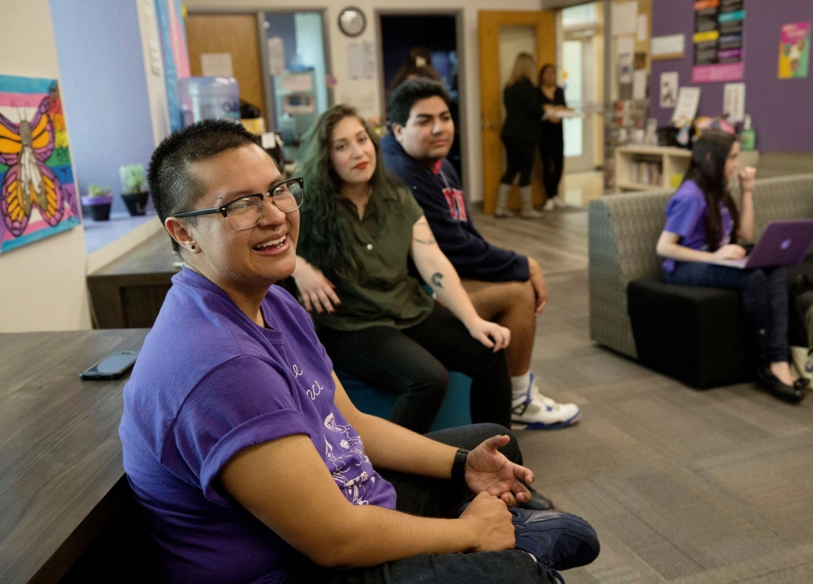 Members of LGBTQ sitting in common area smiling for a photo