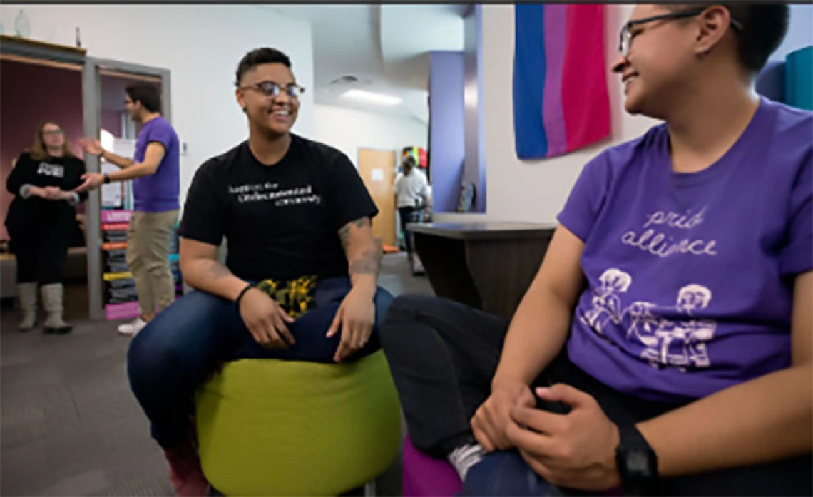 Two members of LGBTQ smiling and talking in common area