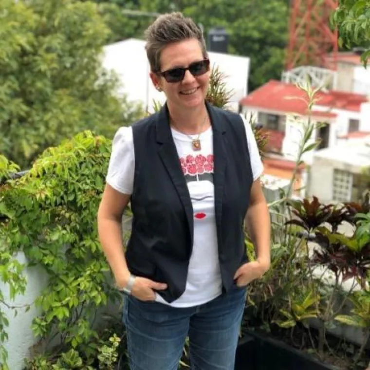 Dr. Jamie A. Lee smiling for photo with plants and buildings in background